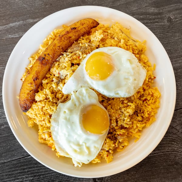 Bolivian Silpancho with fried rice, two sunny-side-up eggs, and a plantain on a white plate.