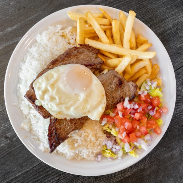 A Bolivian Pique Macho with steak, fried egg, rice, fries, and a side salad.