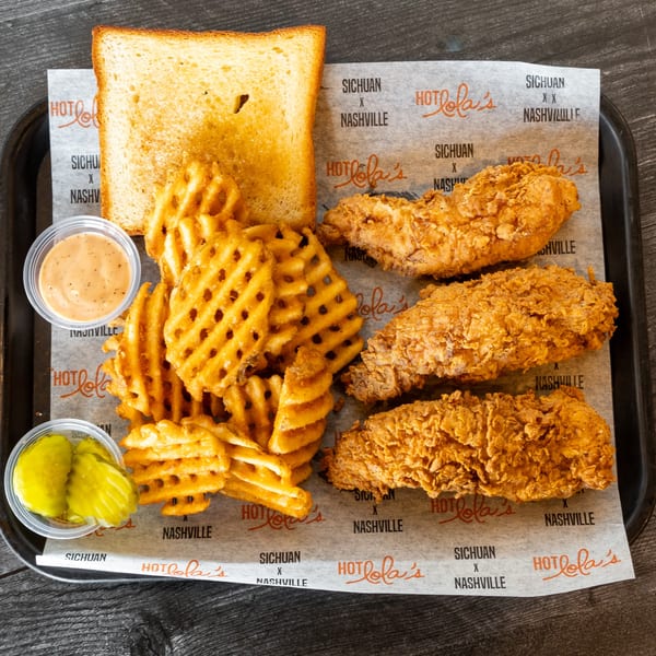 A Hot Lola's fried chicken tender meal with waffle fries, toast, pickles, and dipping sauce.
